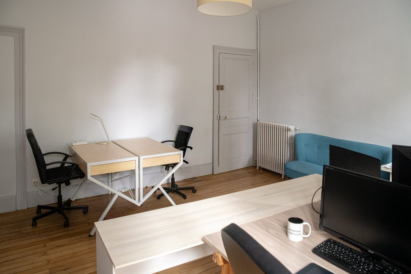Bureau à louer en centre-ville de Limoges avec bureaux, canapé et parquet ancien dans un appartement haussmannien